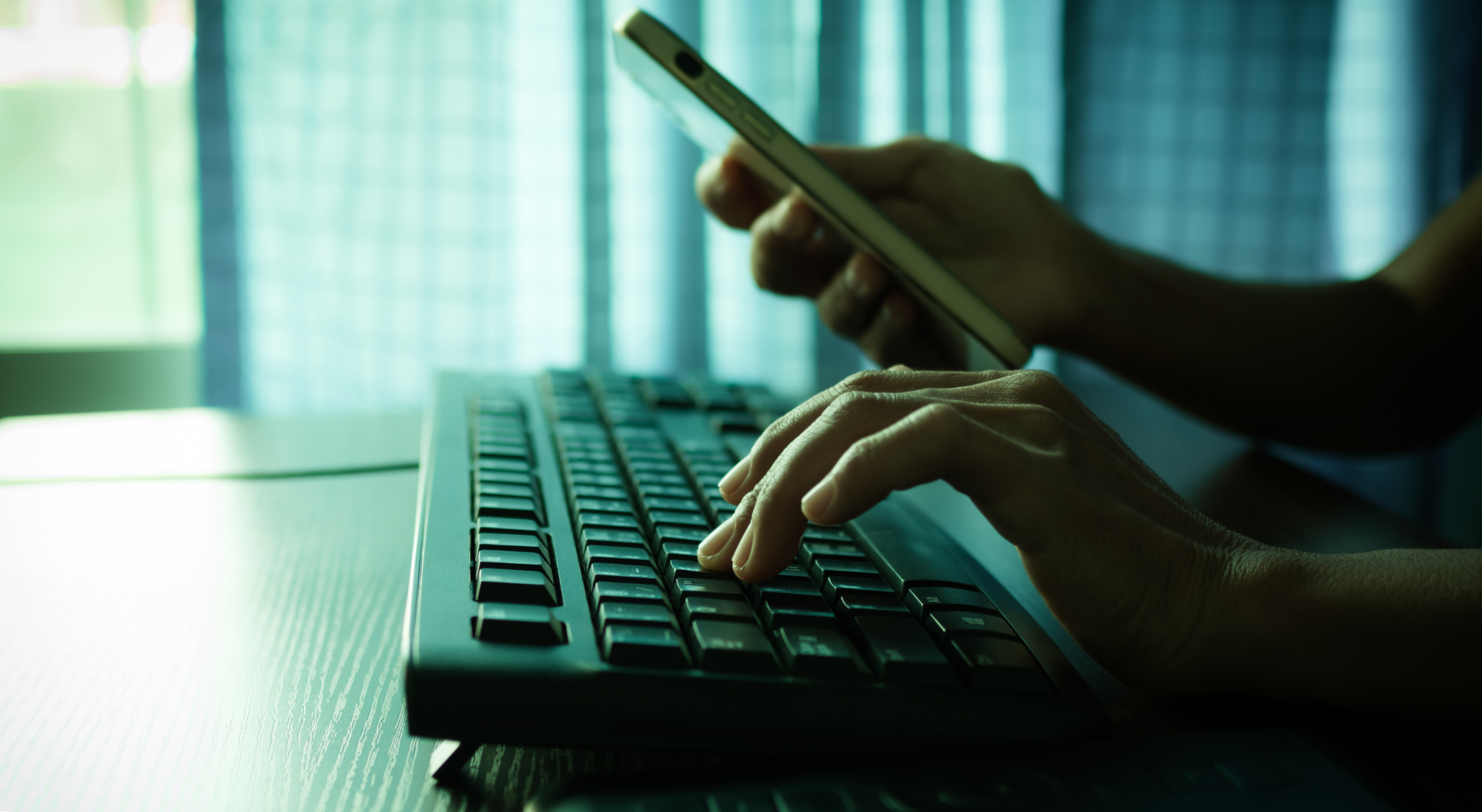 Person using phone and keyboard, searching for signs of identity theft and online fraud activity